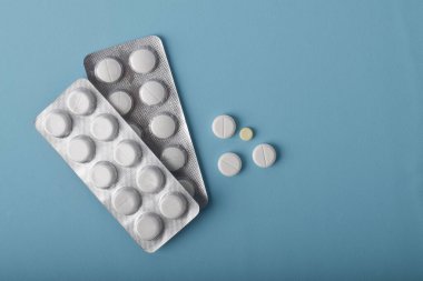 Mavi arka plan, sağlık ve tıp konseptine izole edilmiş su toplayıcı ambalaj tabletleri