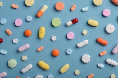 Mavi arka planda renkli hapların, tabletlerin ve kapsüllerin yakın çekimleri, sağlık, eczane ve tıbbi tedavi kavramları için çeşitli ilaçlar ve takviyeleri göstermektedir..
