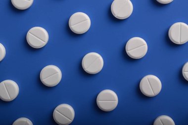 Mavi arka planda düzgün sıralanmış beyaz ilaç deseni. Sağlık ve ilaç konseptleri.