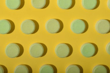 Beyaz ilaç örnekleri sarı arka planda düzgünce sıralanmış. Sağlık ve ilaç konseptleri.