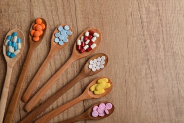 Çeşitli vitamin hapları ve tabletler tahta kaşıklarda, tahta masada, üst tarafta, düz yerde. İlaç kavramı, ilave doz