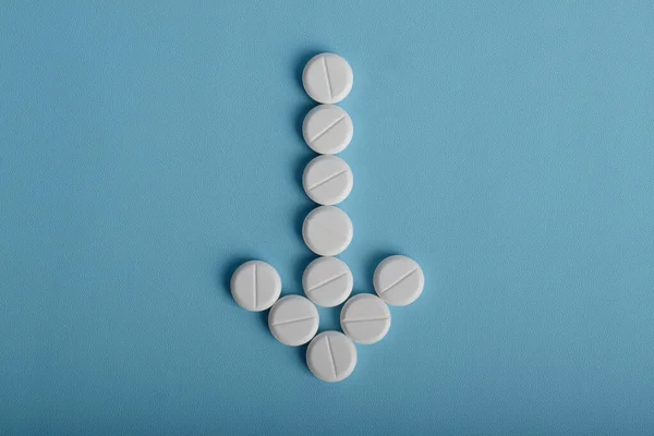 Mavi arka planda izole edilmiş ok şeklinde tıbbi haplar..