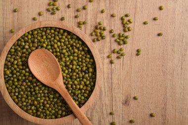 Tahta bir kasede çiğ fasulye, tahta bir masada kaşık, üst manzara. Yemek pişirmek için organik sağlıklı baklagiller, vejetaryen diyeti, fotokopi alanı olan doğal gıda arka planı..