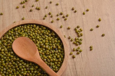 Tahta bir kasede çiğ fasulye ve tahta bir masada kaşık. Organik sağlıklı baklagiller, yemek pişirme, vejetaryen diyeti, doğal gıda geçmişi..