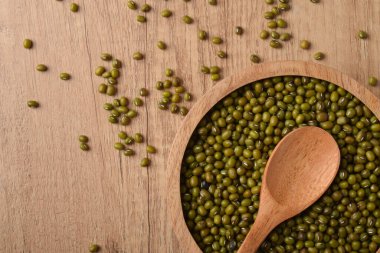 Tahta bir kasede çiğ fasulye, tahta bir masada kaşık, üst manzara. Yemek pişirmek için organik sağlıklı baklagiller, vejetaryen diyeti, fotokopi alanı olan doğal gıda arka planı..