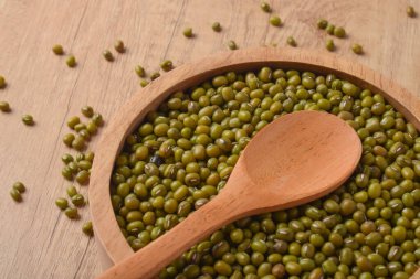 Tahta bir kasede çiğ fasulye ve tahta bir masada kaşık. Organik sağlıklı baklagiller, yemek pişirme, vejetaryen diyeti, doğal gıda geçmişi..