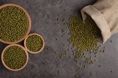 Tahta kaselerde çiğ fasulye ve arka planda çuval bezi. Sağlıklı yemek pişirmek için organik yeşil darbeler..