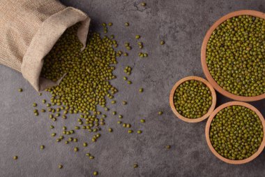 Tahta kaselerde çiğ fasulye ve arka planda çuval bezi. Sağlıklı yemek pişirmek için organik yeşil darbeler..