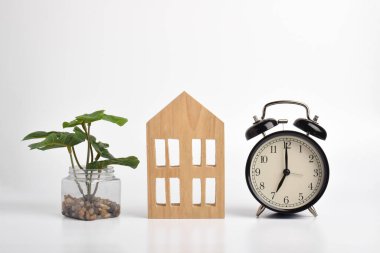 Siyah retro alarm saati ve beyaz arka planda minyatür ev.