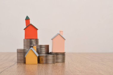 Bozuk paraların üzerinde bir ev. İş kavramları, tasarruflar, iş planlaması ve büyüme, emlak yatırımları, ipotekler, kiralar, vergiler, riskler.