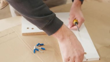 Bir iş yüzeyinde vida ve konnektörler kullanarak bir mobilya parçasının montajı, işçilik ve detaylara dikkat edilmesi, kamera netlik için yakınlaşır