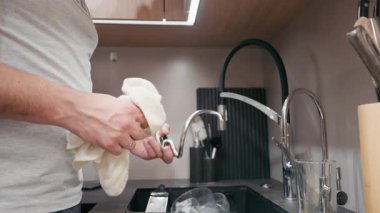 Açık tenli erkek, modern bir mutfakta bulaşıkları kurutuyor, temizlik sürecini ve mutfak elemanlarını vurguluyor, aksiyona yumuşak bir yakınlaştırmayla