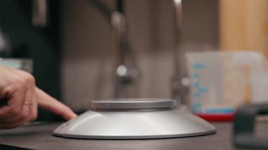 Ekşi hamuru dijital ölçekte pişirmek, dokuları ve doğal elementleri vurgulamak için kullanılan malzemeleri ölçen eller, kamera hareketi yakalamak için yakınlaştırıyor