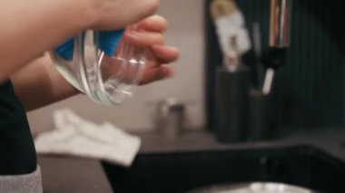 Eller titizlikle cam bir kaseyi mavi bir bezle siler, ekşi mayalı hamur pişirme hazırlama sürecinde dokuyu ve özeni vurgular, kamera hareketi yakından izler.