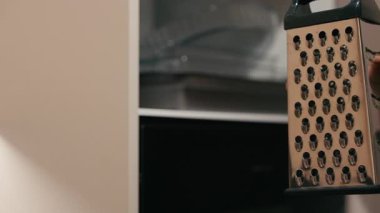 Mutfak ortamında temiz ve modern bir mutfak atmosferiyle, yemek hazırlama eylemini vurgulayarak, dolaptan mutfak rendesi alıyor.