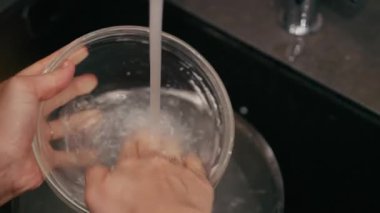 Eller, akan suyun altındaki cam kaseyi titizlikle temizler ve zanaatkar mayalı hamur pişirme sürecinde kullanılan dokuları ve doğal malzemeleri vurgular.