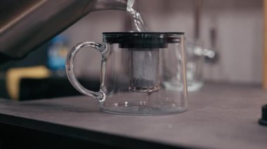 Kehribar çaydanlığı sıcak suyla doludur, zengin kehribar çayına dönüşür, demleme sürecini kamera hareketleriyle vurgular.