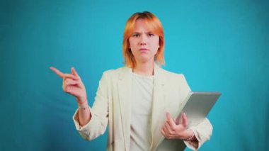 Kendine güvenen genç profesyonel bir kadın dizüstü bilgisayarını tutuyor, parmağını sallıyor, hayır işareti yapıyor, ciddi bir ifadeyle işaret ediyor, bir kınama ve otorite mesajı iletiyor.
