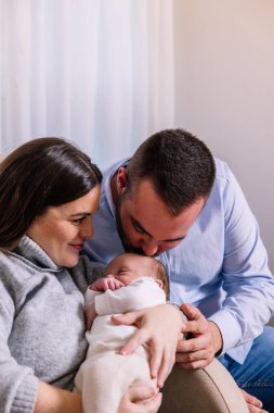 Uyuyan bebeklerini kucaklayan ebeveynler, aile bağlarını, ebeveynliklerini ve yeni yaşamlarını kutlayan şefkatli, barışçıl bir sevgi, koruma ve bağlantı anlarını paylaşıyorlar.