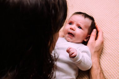 Anne-baba sevgiyle ağlayan yeni doğmuş bir bebeği kucağında tutuyor, sıkıntı anında rahatlık ve bakım sağlıyor, aile bağının güçlü yönünü ve bakımı vurguluyor