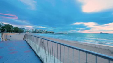 Levante sahilindeki Benidorm şehrinin güzel manzarası. Arka planda ikonik ada, İspanya 'da popüler bir turizm merkezi. Şafakta gezinti güvertesi ve sakin dalgaları gösteriyor.