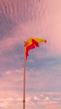 İspanya 'nın görkemli ulusal bayrağı bayrak direğinde dalgalanırken güzel pembe ve mor bir günbatımı gökyüzüne karşı bulutlarla İspanya' nın gururunu, özgürlüğünü ve ulusal kimliğini kutluyor.