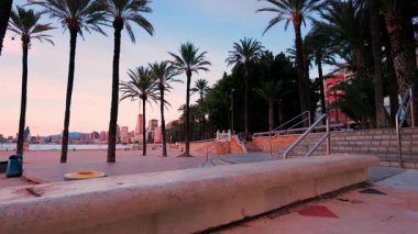 Dolly, benidorm, İspanya 'da Poniente plajı boyunca ilerlerken, gökdelenlerle gökdelenleri ve gökdelenleri gösteren pembe ve mavi renklerle güzel bir günbatımı gökyüzüne karşı çekim yaptı.