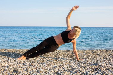 Kumsalda egzersiz yapan bir kadın.