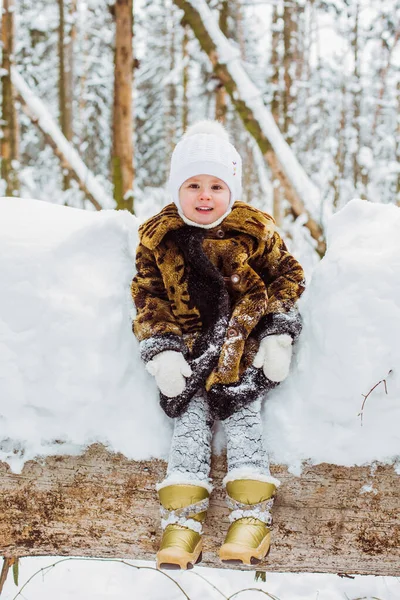 Ritratto invernale di ragazza bambino carina sorridente sulla passeggiata nella foresta innevata soleggiata — Foto Stock