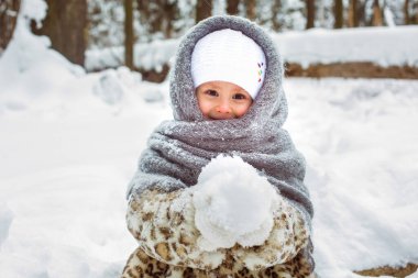 Güneşli bir ormanda yürüyüş yapan sevimli, gülümseyen bir kızın kış portresi.