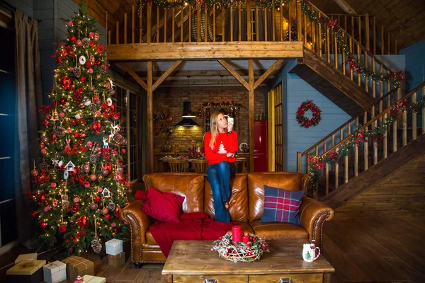 Noel ağacının önünde oturan kız.