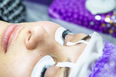 Spa salonundaki kadın takma kirpik takıyor.