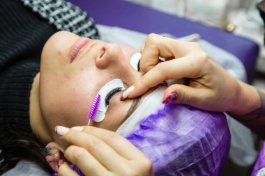 Spa salonundaki kadın takma kirpik takıyor.