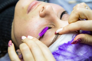 Spa salonundaki kadın takma kirpik takıyor.