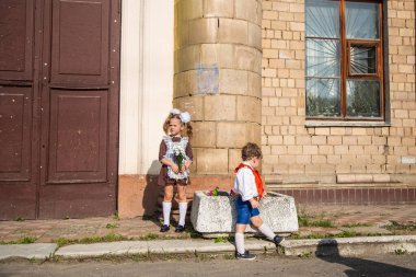 Okul üniformalı çocuklar okulun yanında yürürler ve yemek yerler.