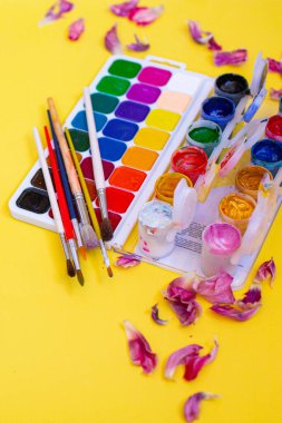 Aquarelle paleti ile yaratıcı düzen, sarı arkaplanda boya fırçaları