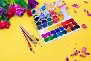 Aquarelle paleti ile yaratıcı düzen, sarı arkaplanda boya fırçaları