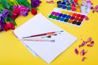 Aquarelle paleti ile yaratıcı düzen, sarı arkaplanda boya fırçaları