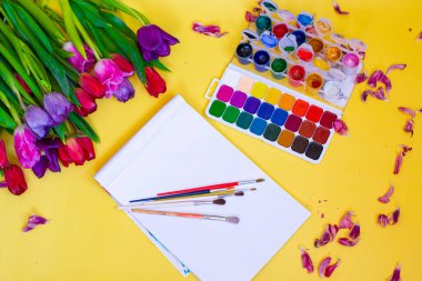 Aquarelle paleti ile yaratıcı düzen, sarı arkaplanda boya fırçaları