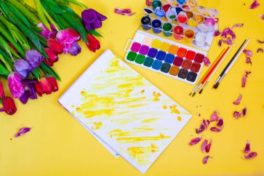Aquarelle paleti ile yaratıcı düzen, sarı arkaplanda boya fırçaları