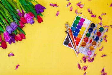 Aquarelle paleti ile yaratıcı düzen, sarı arkaplanda boya fırçaları