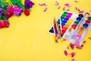Aquarelle paleti ile yaratıcı düzen, sarı arkaplanda boya fırçaları