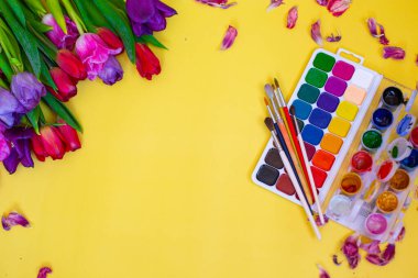 Aquarelle paleti ile yaratıcı düzen, sarı arkaplanda boya fırçaları