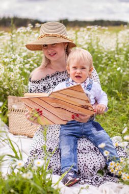 Güzel kadınlar ve oğlu oturmuş kitap okuyorlar.
