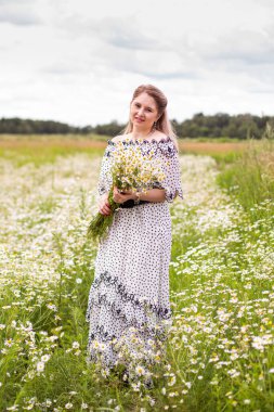 Tarlada çiçeklerle güzel bir kadın.
