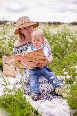 Güzel kadınlar ve oğlu oturmuş kitap okuyorlar.