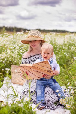 Güzel kadınlar ve oğlu oturmuş kitap okuyorlar.