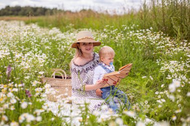 Güzel kadınlar ve oğlu oturmuş kitap okuyorlar.