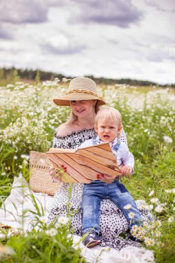 Güzel kadınlar ve oğlu oturmuş kitap okuyorlar.
