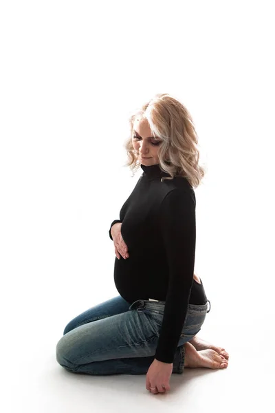 Ung smuk gravid kvinde stående på lyserød baggrund - Stock-foto